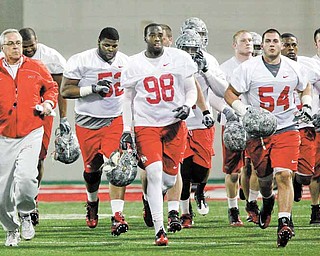 FILE - In this March 31, 2011 file photo, Ohio State defensive coach Jim Haycock, left, runs with a group of defensive players during the first day of NCAA college football practice  in Columbus, Ohio.  Even though most of the starters from a year ago have graduated, one of the biggest surprises at Ohio State this spring is the effectiveness of the Buckeyes defense. (AP Photo/Terry Gilliam)