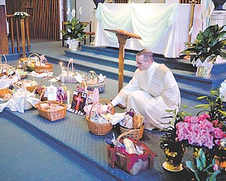 Nick Moliterno, deacon at Immaculate Heart of Mary Church in Austintown, lights candles near Easter baskets filled with parishioners’ holiday food.