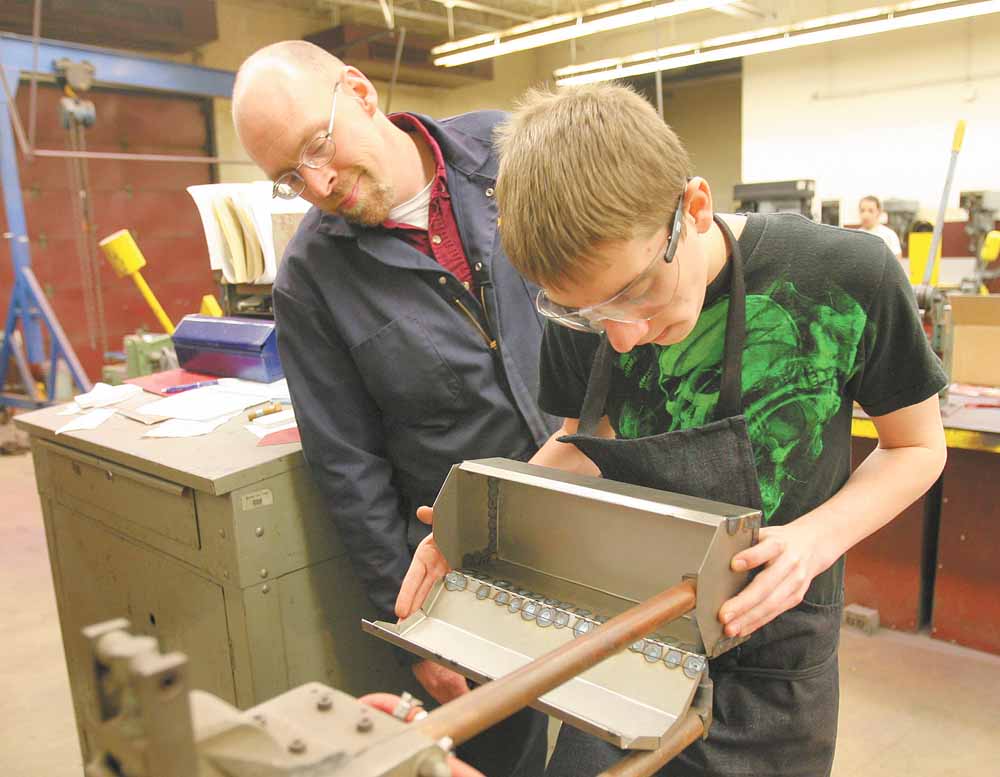 Instructor Michael Powell observes as first year student Rib Tullio, a freshman, spot welds a tool box he designed.