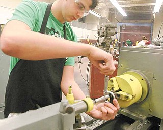 Boardman sophomore Scott Glenn works on a machine lathe as he measures a handle for the vise he is constructing.