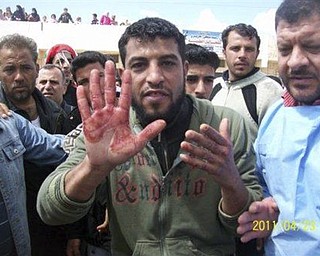 In this citizen journalism image made on a mobile phone and acquired by the AP, a Syrian anti-government protester holds up a bloodied hand during a funeral procession for slain activists in Izraa, Syria, Saturday, April 23, 2011. Syrian security forces fired on tens of thousands of mourners during funeral processions Saturday, killing several people following the deadliest day of the uprising against authoritarian President Bashar Assad. 