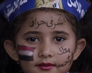 A Yemeni girl looks on during a rally supporting President Ali Abdullah Saleh, in Sanaa,Yemen, Friday, April 22, 2011.  Opponents and supporters of Yemen's embattled president are marching in cities and towns across the nation for rival rallies after Friday prayers. Arabic reads on her face, " We are with you".