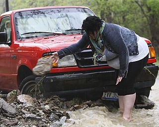 Katie Shook, of Sedamsville, moves rocks and stones from around her brother's truck that were washed down Fairbank Avenue from heavy rainfall, Saturday, April 23, 2011, in the Sedamsville community of Cincinnati.