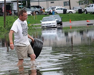 John Brisentine walks through water nearly up to his knees Monday, April 25, 2011 as he carries a tire he found near the submerged intersection of 3rd and Vienna streets in Metropolis, Ill. The Ohio River is threatening homes in that part of the city.