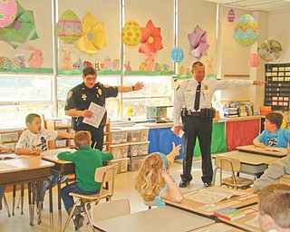 The right way: During a “Safety On Wheels” program presented by Hubbard Optimist Club on April 15 at St. Patrick School in Hubbard, from left, Lou Carsone, acting Hubbard City Police Chief, and Todd Coonce, Hubbard Township Police Chief, taught second-grade students proper hand signals to use while riding their bikes on roadways. During the bike safety program the students also learned that if a city or township police officer sees them wearing a helmet while riding a bike, they will receive a certificate for a free treat from Hubbard Dairy Queen. Following the bike safety program the Optimist Club gave each student a new bike helmet.