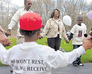 Elder Rose Carter, center, leads family and friends of Vivian Martin in prayer at the Nelson Avenue house where Martin was murdered.