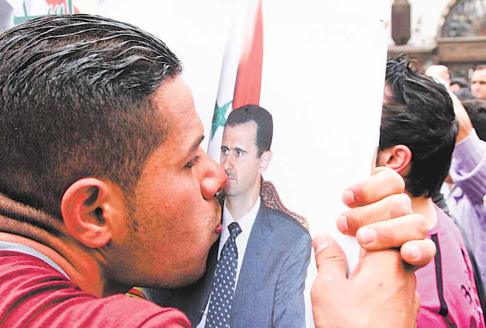 A Syrian pro-government supporter kisses a picture of Syrian President Bashar Assad during a protest to show support to the Syrian regime in old Damascus, Syria, Saturday, April 30, 2011, pictured on a government-provided tour. Syrian army troops backed by tanks and helicopters on Saturday took a prominent mosque that had been controlled by residents in a besieged southern city, killing four people, a witness said.