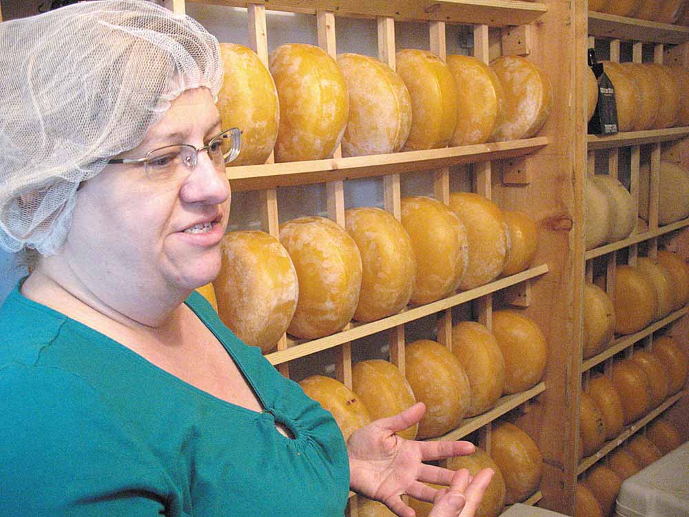 Susan Morris of Mayfield Road Creamery talks about raw-milk cheese production while showing a cooler filled with aging Gouda cheese wheels. 
