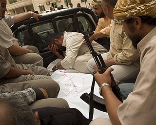 A Libyan man, center, cries next the body of a Libyan rebel fighter at Hikma hospital in the besieged city of Misrata, Libya, Saturday, April 30, 2011. Libyan leader Moammar Gadhafi called for a cease-fire and negotiations with NATO powers in a live speech on state TV early Saturday, just as NATO bombs struck a government complex in the Libyan capital. 