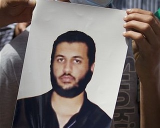 In this photo made on a government organized tour, Libyans hold a photo of Moammar Gadhafi's son Seif al-Arab given by a Libyan official, in Tripoli, Libya, Sunday, May 1, 2011. Libyan leader Moammar Gadhafi escaped a NATO missile strike in Tripoli that killed one of his sons and three young grandchildren, a government spokesman said early Sunday.