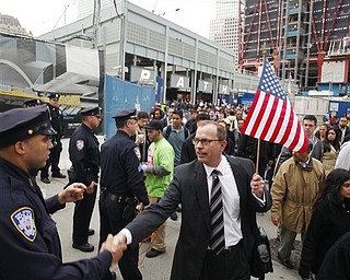 A commuter holds an American flag while shaking hands with a police officer at the World Trade Center site in New York on Monday, May 2, 2011. Under construction, the Freedom Tower is seen at top right.