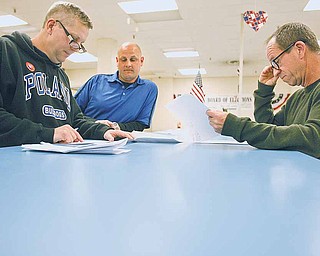 Paul McFadden, left, chairman of the Citizens Committee for Poland Schools, Eric Ungaro, center, committee vice chairman, and Michael Morley, a member of the Mahoning County Board of Elections, go over the results of the Poland School levies at the board offices in Youngstown. The school district’s renewal levy passed, but the additional levy failed in Tuesday’s election.