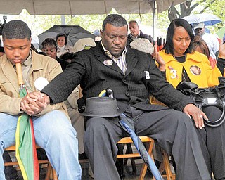 From left, Jamail Johnson’s brother, Sidney Hill; step-father, Sidney Hill; and mother, Shirlene Hill, join hands in prayer Tuesday afternoon during a tree-planting ceremony at Youngstown State University. A burr oak tree was planted at the YSU campus core in Johnson’s memory. He was shot and killed Feb. 6 while trying to break up a fight at an off-campus party.