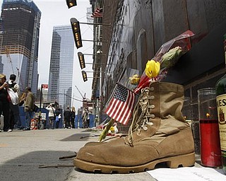 A pair of military boots, a bottle of whiskey and a memorial candle are placed at the base of a 9-11 memorial across the street from ground zero in New York, Tuesday, May 3, 2011. The boots and other items were placed there with a sign that reads, "Today let us pray for peace." Foot traffic has increased at ground zero from tourists and locals alike in the wake of the death of Osama bin Laden in a U.S.-led raid in Pakistan Sunday.