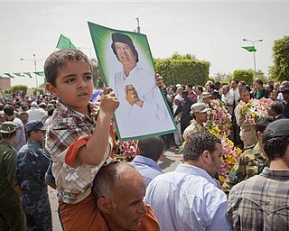 In this photo made on a government organized tour, supporters attend funeral ceremony for members Gadhafi family in Tripoli, Libya, Monday, May 2, 2011. A NATO missile strike in Tripoli killed Gadhafi's son Seif al-Arab and his three young grandchildren. 
