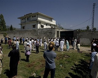 Local people and media gather outside the perimeter wall and sealed gate into the compound and a house where al-Qaida leader Osama bin Laden was caught and killed late Monday, in Abbottabad, Pakistan, on Tuesday, May 3, 2011. Local residents showed off small parts of what appeared to be a U.S. helicopter that Washington said malfunctioned and was disabled by the American commando strike team as they retreated, while Pakistan's leader on Tuesday denied suggestions that his country's security forces had sheltered Osama bin Laden.