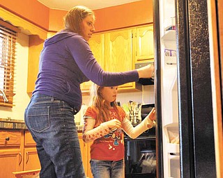 Laurie Thompson, left, is a mother of three and is a surrogate mother of twins for a couple in Spain, the second time she has been a surrogate. Thompson helps her daughter Avery open a new refrigerator at home in McHenry, Illinois, on April 4, 2011.