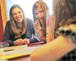 Laurie Thompson, left, is a mother of three and is a surrogate mother of twins for a couple in Spain, the second time she has been a surrogate. Thompson helps her daughters Avery and Kyrra, right, with homework at home in McHenry, Illinois, on April 4, 2011.