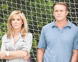 In this film publicity image released by Warner Bros., Sandra Bullock, left, and Tim McGraw are shown in a scene from, "The Blind Side."