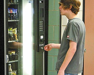 Will Kooyman, a junior at Boardman High School, puts money in one of the school-owned snack vending machines in the cafeteria. Public health and school offi cials are on a mission to reduce calories and improve nutrition of items sold to students in Mahoning County schools.