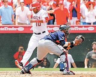 Los Angeles Angels' Vernon Wells (10) scores ahead of the throw to Cleveland Indians catcher Carlos Santana (41) on a double by the Angels' Alberto Callaspo (not pictured) during the sixth inning of a baseball game in Anaheim, Calif., Sunday, May 8, 2011.