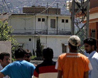 Pakistani youths view the house, background, of former al-Qaida leader Osama bin Laden in Abbottabad, Pakistan on Sunday, May 8, 2011. Osama bin Laden was killed by a helicopter-borne U.S. military force on Monday, in a fortress-like compound on the outskirts of Pakistani city of Abbottabad.