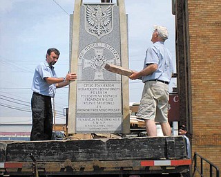 Workers from O.T. Beight & Sons Inc. monument company of Boardman load a monument to Polish veterans of World Wars I and II onto a truck last week after removing it from the front of the vacant former Krakusy Hall in Youngstown. The monument will be rededicated June 25 in Peterson Park in Poland.