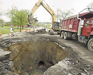 Youngstown Street Department workers remove debris from a sinkhole on Belmont Avenue. An aged sewer line collapsed, causing the ground to erode beneath the North Side street. The collapse took place either late Sunday night or early Monday.