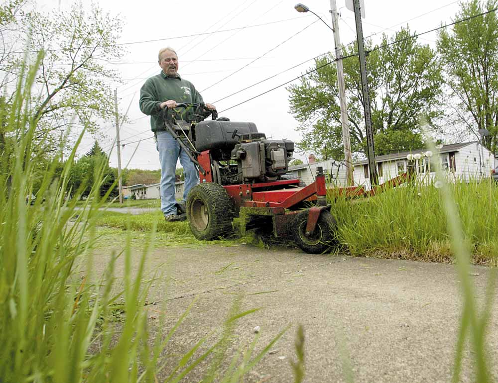 John Foty of Foty’s Lawn Service mows grass on Iowa Street in Girard on Tuesday. The rainy weather has slowed his business, forcing him to cut 50 to 60 fewer lawns a week.