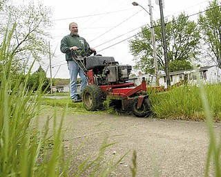 John Foty of Foty’s Lawn Service mows grass on Iowa Street in Girard on Tuesday. The rainy weather has slowed his business, forcing him to cut 50 to 60 fewer lawns a week.