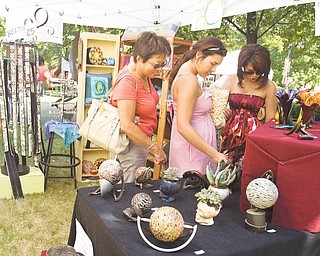 From left, Kim Powell, with Anna and Lydia, look at artwork by Tony Armeni at the Youngstown State University Summer Festival of the Arts 2010.