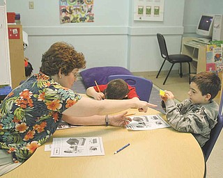 Ann Ferguson helps Brendan Baird and Justin Clark with a visual exercise at The Potential Development Center, designed to give easily distracted autistic children a structured environment.