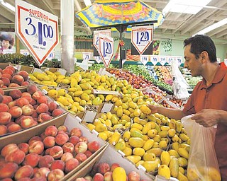 In this May 23, 2011 photo, customer Gabriel Sanchez shops for fresh fruit at a Superior Grocers store in Los Angeles. Consumer spending rises but much of gain goes to pay for higher food and energy Friday, May 27, 2011.(AP Photo/Damian Dovarganes)