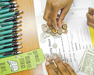 A Taft Elementary student counts the change deposited by a fellow student in a program on banking.