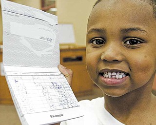 At right, Taft Elementary School kindergartner Michael Logan shows the bank book he’s been using to keep track of deposits to his savings account. The Kids Club, a banking program from Huntington Bank, allows children to learn about saving money and the operations of a bank.