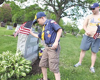 Jack Brant, 8, and his father, Chad Brant, both of Poland, place flags at the graves of veterans Saturday at Poland Riverside Cemetery. Jack is a member of Cub Scout Pack 44,  one of several groups performing the annual pre-Memorial Day task at the cemetery.