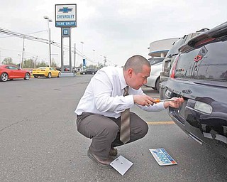 Dustin Hager moves license plates from one car to a new Chevy he sold at Hank Graff Chevrolet in Davison, Michigan, on May 13, 2011. (Eric Seals/Detroit Free Press/MCT)
