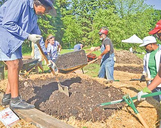 Elisabeth Stocking of St. Louis and Maurice Small of Cleveland dump a load of leaf compost into a raised garden plot for a new community garden on the East Side of Youngstown.