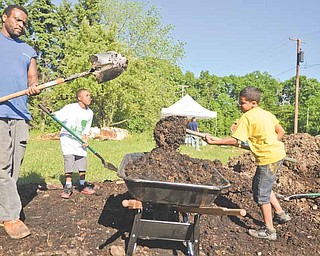 Johnny Eiland, left, Keith Foster, 10, and Samuel Rivera, 9, of Youngstown shovel soil into a wheelbarrow to use for a raised-bed garden plot.