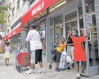 In this photo taken May 29, 2011, Teyonce Armstrong, right, 7, and her brothers Keith, 6, and Markquis, 11, play by the door of a Harlem Deal$ store in New York while waiting for their grandmother, who was shopping inside, to exit. Deal$ stores are owned by Dollar Tree, which sells a variety of items for $1. The company said at the end of May it continues to see more customers who are spending more per visit. Dollar stores pose the biggest threat Wal-Mart, the nation's biggest retailer. (AP Photo/Kathy Willens)