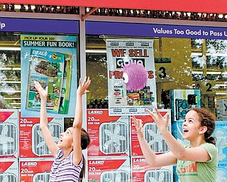 In this photo taken May 29, 2011, young girls play as they pass a Harlem Deal$ store in New York, where a six-ounce New York strip steak can be purchased for $1.50. Deal$ stores are owned by Dollar Tree, which sells a variety of items for $1. As May came to a close, the company said it continues to see more customers who are spending more per visit. Dollar stores pose the biggest threat Wal-Mart, the nation's biggest retailer. (AP Photo/Kathy Willens)