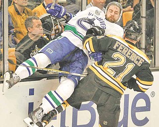 Boston Bruins defenseman Andrew Ference (21) checks Vancouver Canucks left wing Christopher Higgins (20) in the first period during Game 3 of the NHL hockey Stanley Cup Finals on Monday, June 6, 2011, in Boston. (AP Photo/Winslow Townson)