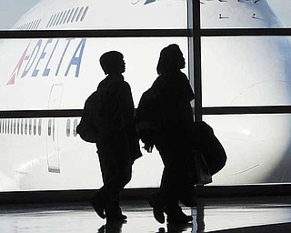 FILE - In this Jan. 21, 2010 file photo, passengers walk past a Delta Airlines 747 aircraft in McNamara Terminal at Detroit Metropolitan Wayne County Airport in Romulus, Mich. Reacting to public outcry, Delta said Wednesday, June 8, 2011, it will allow members of the military to check four bags for free. The news came after two Army soldiers returning from Afghanistan complained in an online video that Delta charged their unit a total of $2,800 when some of them checked a fourth bag.(AP Photo/Paul Sancya, file)