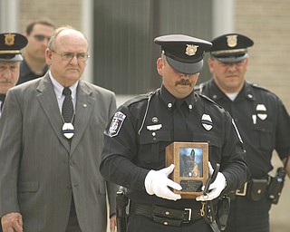 ROBERT K. YOSAY | THE VINDICATOR..New Castle PD Terry Dolquist ( CHICOS FIRST HANDLER- NOT THE HANDLER WHO IS RESPONSIBLE -)  Carries the cremains and Chico's leash to the ceremony ----Chico - New Castle Police K-9 Officer was honored today with a memorial service and  a memorial drive thru the city. Chico died Saturday after being left in a police car for almost three hours. The handler -officer- who has not been named is suspended without pay...-30-