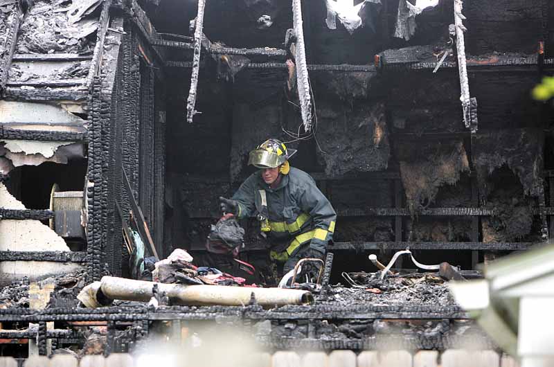 A firefighter looks for clues after a fire that killed four children and two adults in Warren. The fire at 911 Landsdowne Ave. NW was reported at 4:43 a.m. Thursday..