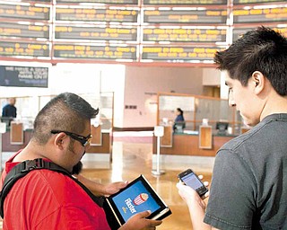 In this June 15, 2011 photo, moviegoers Luis Garcia, 37, left, and Elias Sanchez 26, watch movie trailers on Flixster on their iPad and iPhone, before buying their tickets at the ArcLight Hollywood cinema in Los Angeles. Theater owners have tried a variety of methods to get folks to keep quiet and stay off their phones during shows, from playing amusing messages beforehand to having ushers sweep through the auditorium during the show, said John Fithian, president of the National Association of Theatre Owners. (AP Photo/Damian Dovarganes)