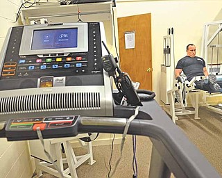 Hubbard Township Police Officer Greg Tarr works out on a leg machine in the new exercise room at Hubbard Township Police Department. The department received some donated equipment, and Fraternal Order of Police Lodge 85 bought other pieces including a treadmill, in foreground. Tarr said the exercise equipment will help increase officers’ fitness.