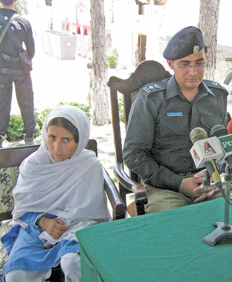 Sohana Jawed, left, a nine year old Pakistani girl sits with police chief Salim Marwat during a news conference in Lower Dir in Timergarah, Pakistan on Monday, June 20, 2011. A 9-year-old girl who was kidnapped on her way to school and forced to wear a suicide vest managed to escape her captors Monday as they directed her to attack a paramilitary checkpoint in northwest Pakistan. (AP Photo/M. A. Khan)