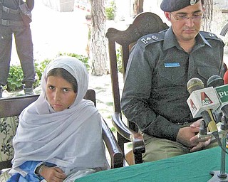 Sohana Jawed, left, a nine year old Pakistani girl sits with police chief Salim Marwat during a news conference in Lower Dir in Timergarah, Pakistan on Monday, June 20, 2011. A 9-year-old girl who was kidnapped on her way to school and forced to wear a suicide vest managed to escape her captors Monday as they directed her to attack a paramilitary checkpoint in northwest Pakistan. (AP Photo/M. A. Khan)