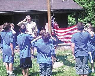 Cub Scouts host family event at camp: Cub Scout Master Troy Homrighausen leads Pack 25 of Canfield United Methodist Church in the flag raising at Camp Akela during Family Camp. The Scouts hosted their families, who joined them June 4 for a day of nature and nurturing, which included flag ceremonies, tug-of-war events, hiking, a camp cleanup and rocket building.